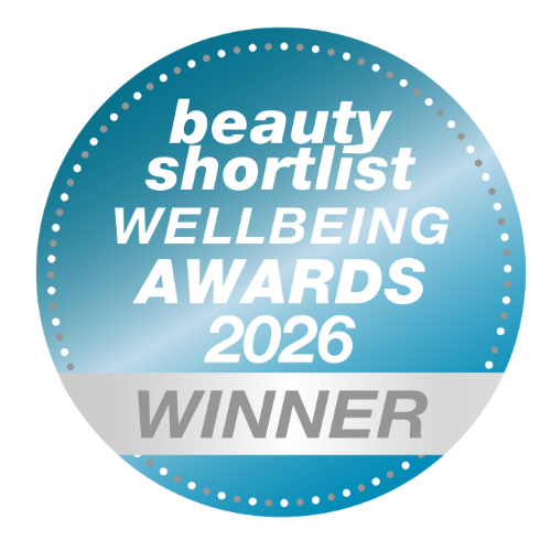 A circular blue badge with white text reading 'beauty shortlist WELLBEING AWARDS 2026 WINNER' on a white background.