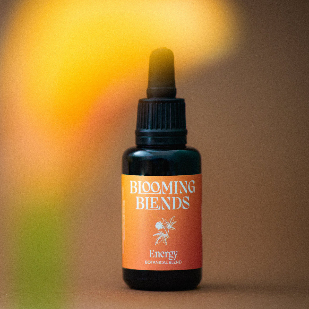 Blooming Blends Energy tincture bottle in warm golden light