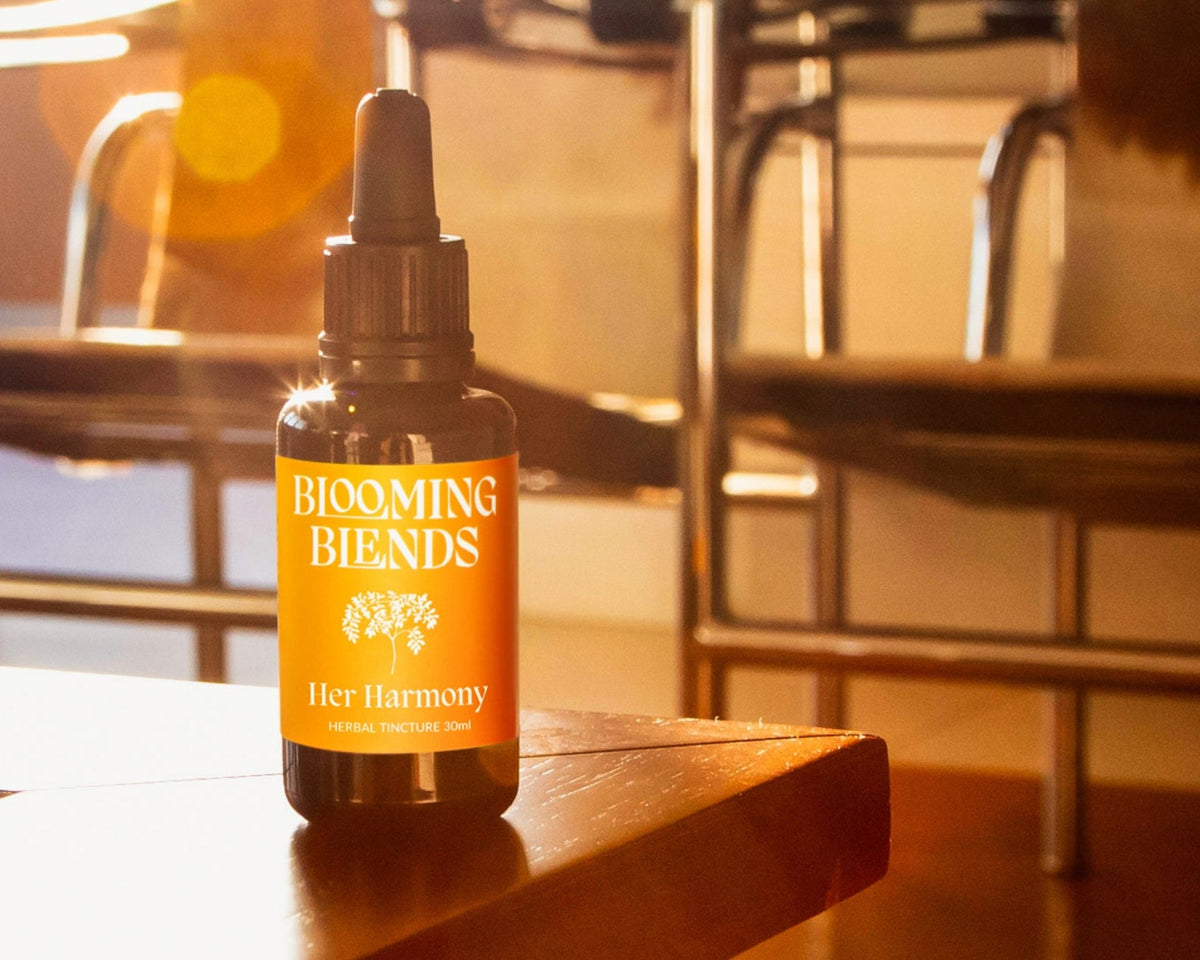 Blooming Blends Her Harmony tincture bottle on a wooden table in warm sunlight