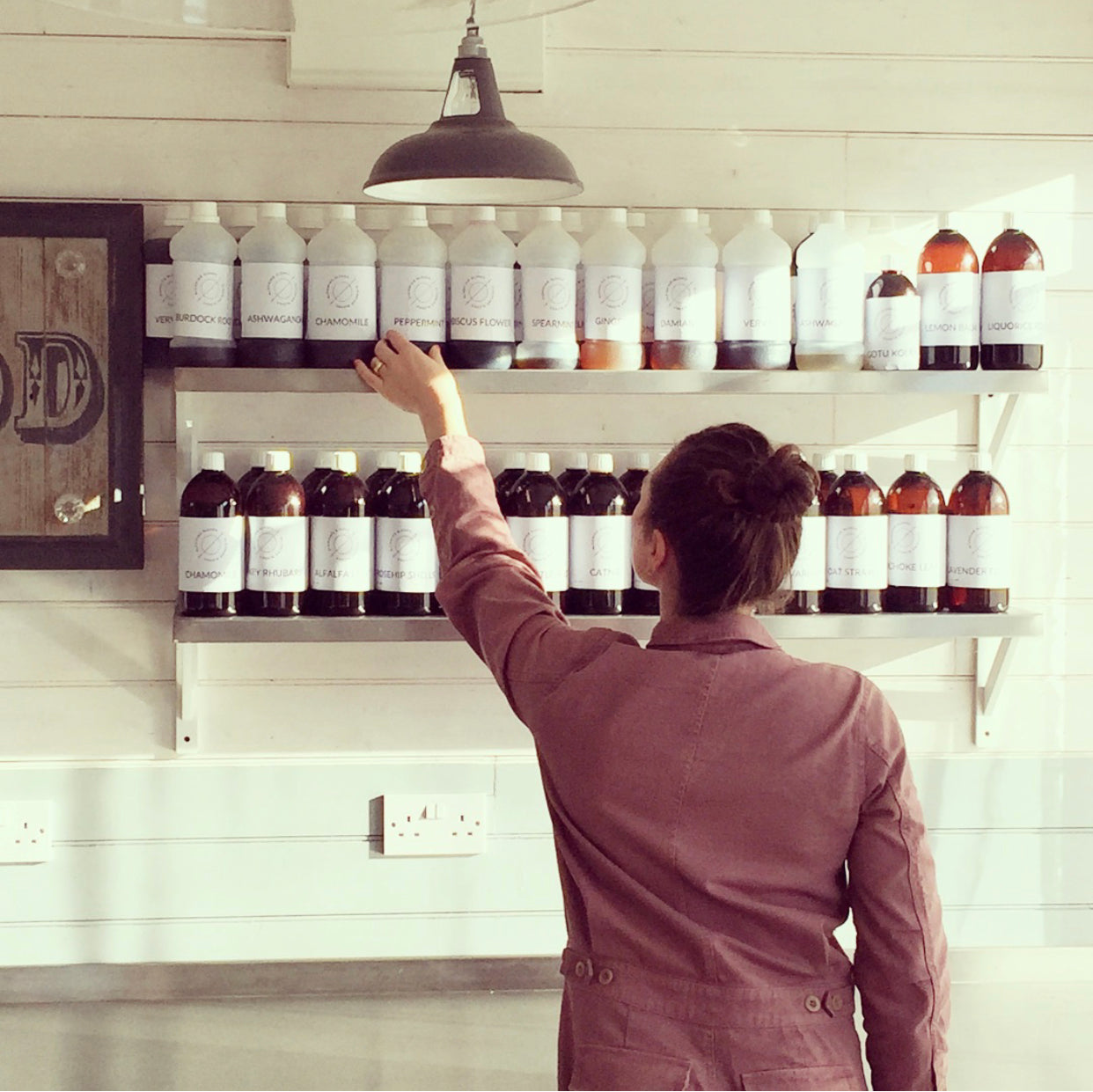 Two Blooming Blends herbal tincture bottles displayed on stone blocks with flowers.