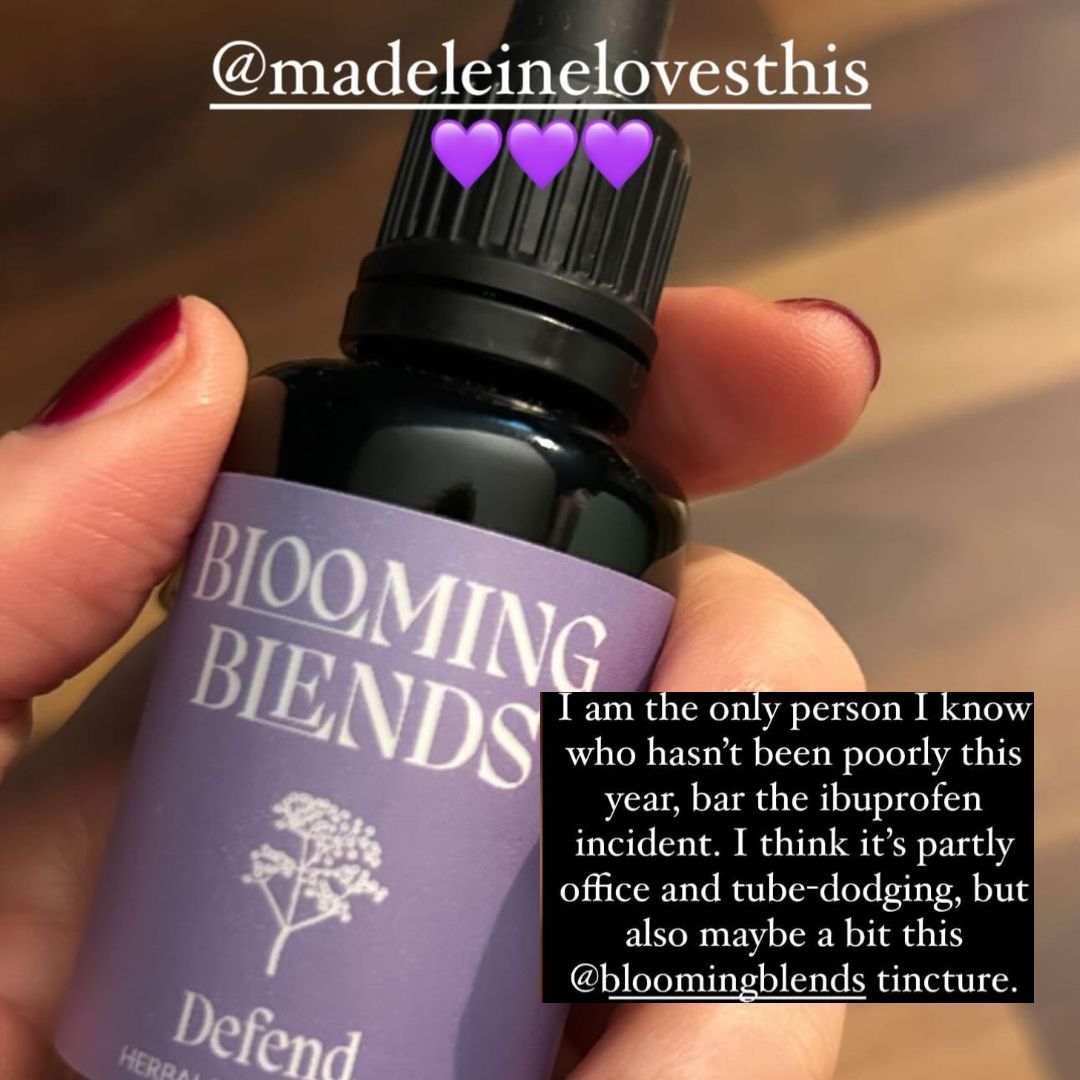 Hand holding a 'Blooming Blends' tincture bottle with text overlay. Immune booster